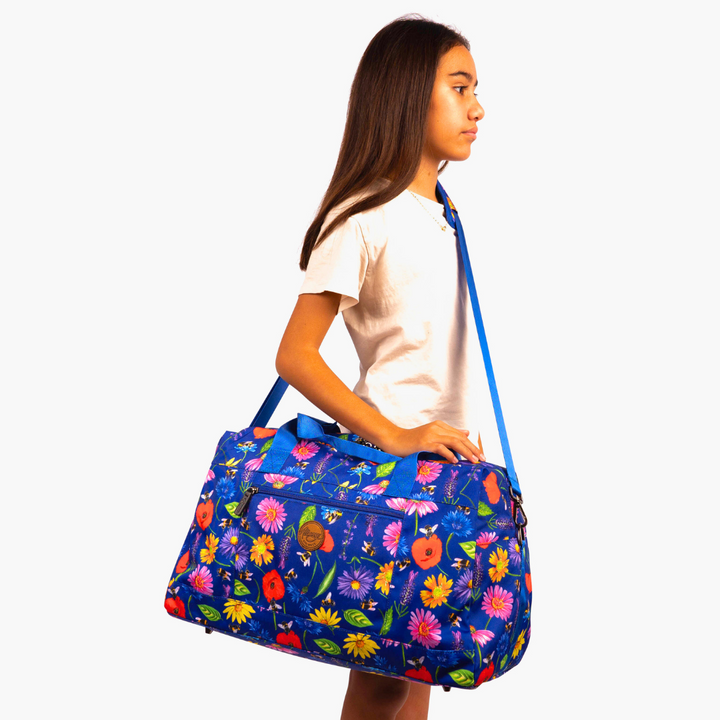 girl wearing blue alimasy bees and wildflowers kids duffle bag across body