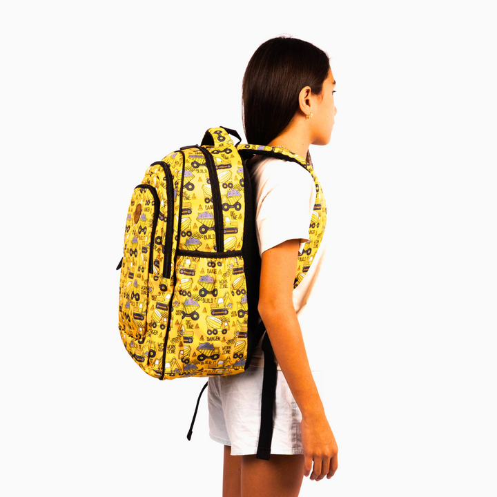 side view of girl wearing yellow backpack with construction trucks and diggers pattern